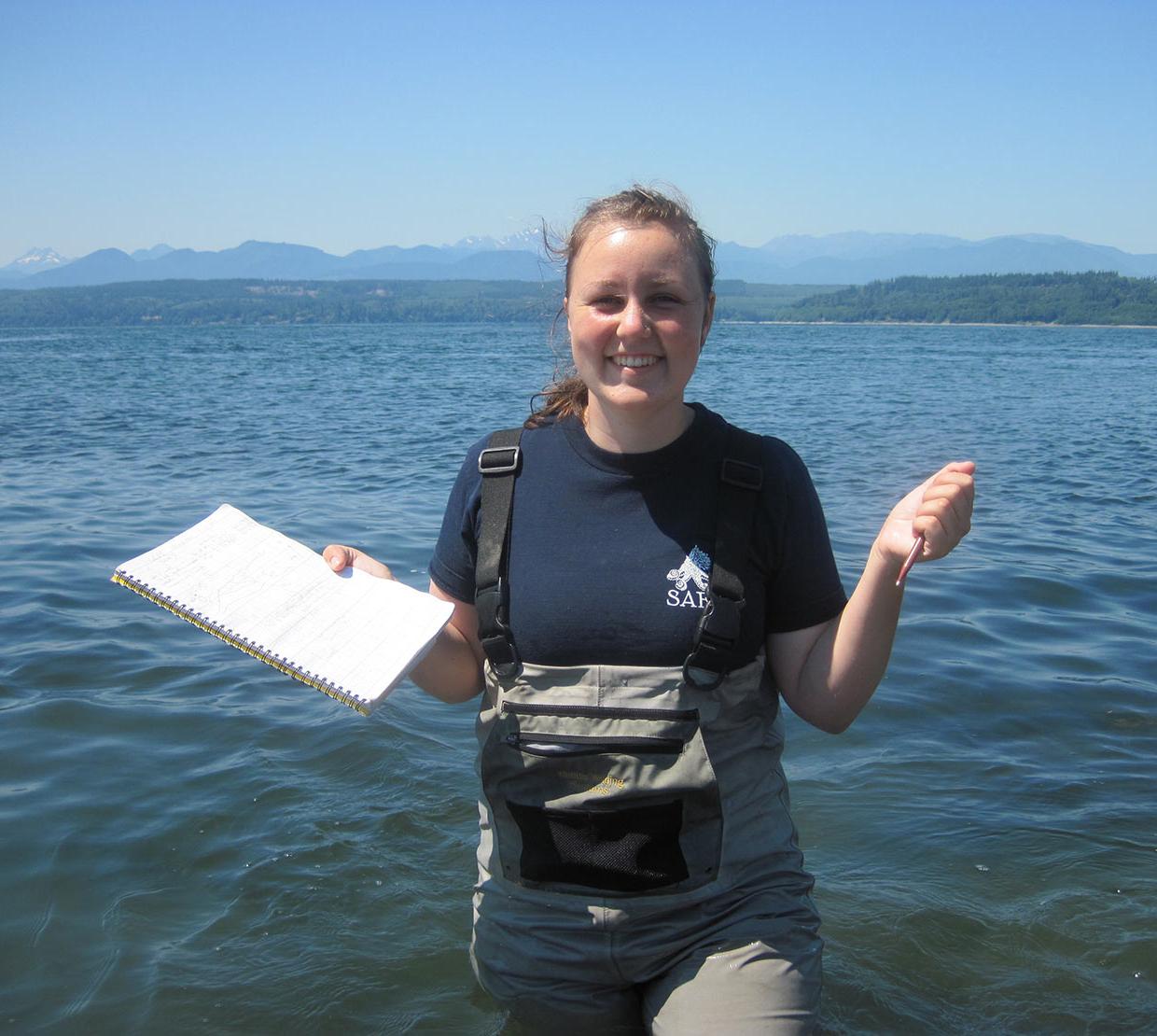 Shannon Hennessey standing in ocean with pen and paper