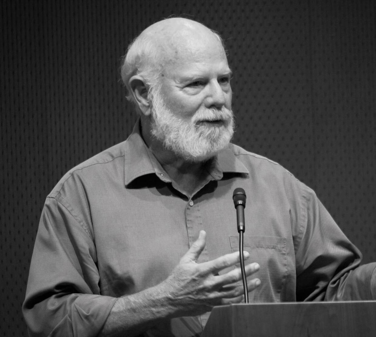 Image of Stevan J. Arnold: A male professor in short sleeve button-up shirt speaking at a podium.
