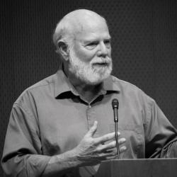 Image of Stevan J. Arnold: A male professor in short sleeve button-up shirt speaking at a podium.
