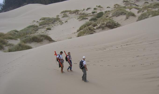 three people walking through Oregon sand dunes
