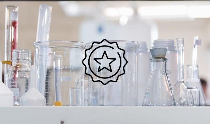 A star badge icon above an image of beakers and lab equipment sitting on a lab table.