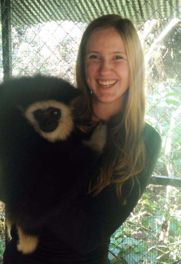 Karianna Crowder holding a white-cheeked gibbon in enclosure