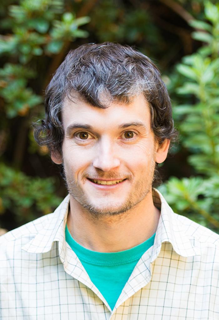 Nathan Kirk smiles in a headshot image with a button-up shirt.