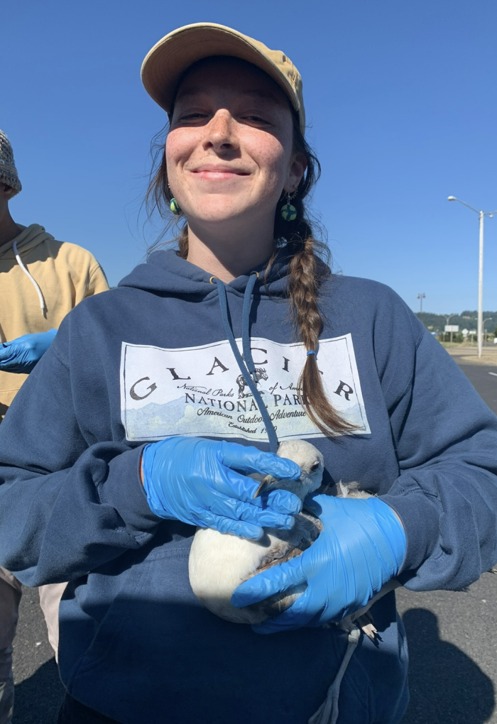 A woman in a blue sweatshirt holds a bird.