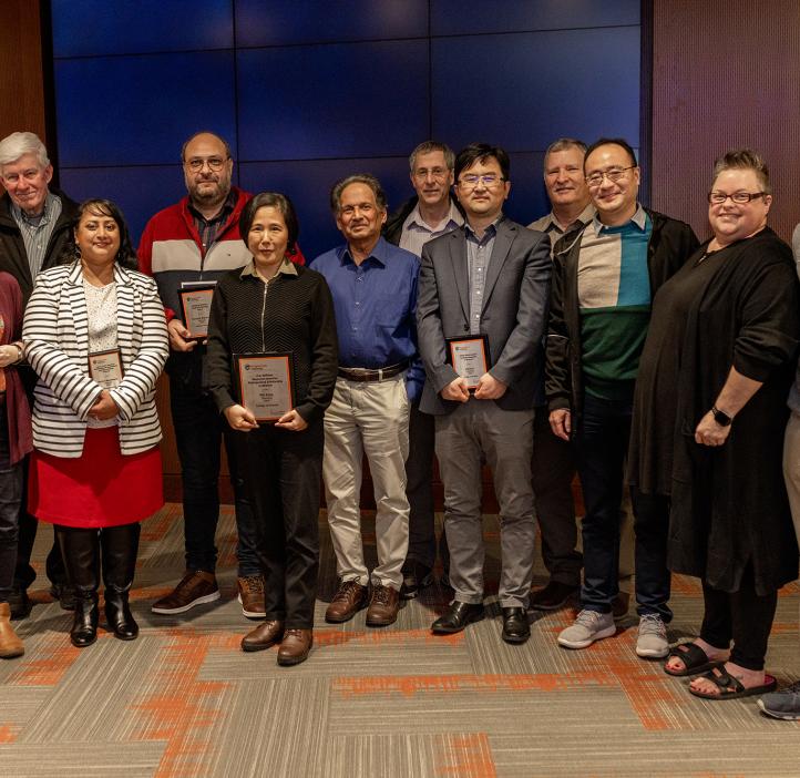 Group of faculty and family standing with awards.