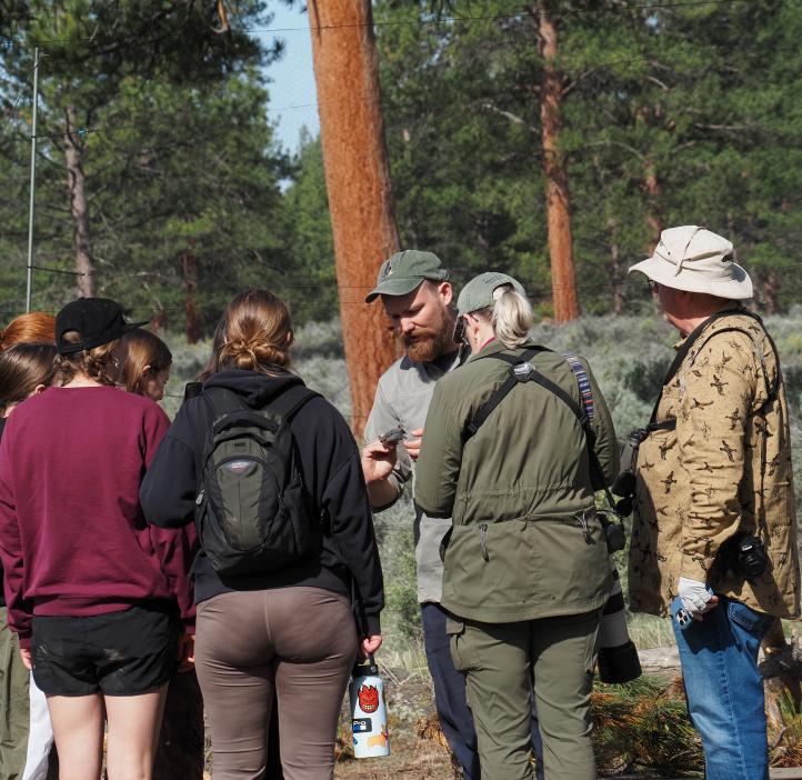Students gather around a researcher holding a bird.