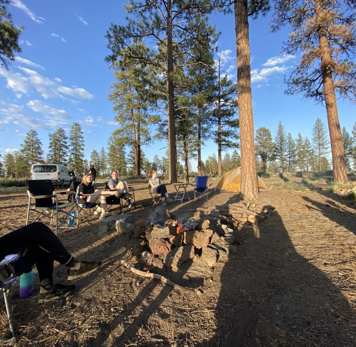 Students relax in camp chairs at campsite.